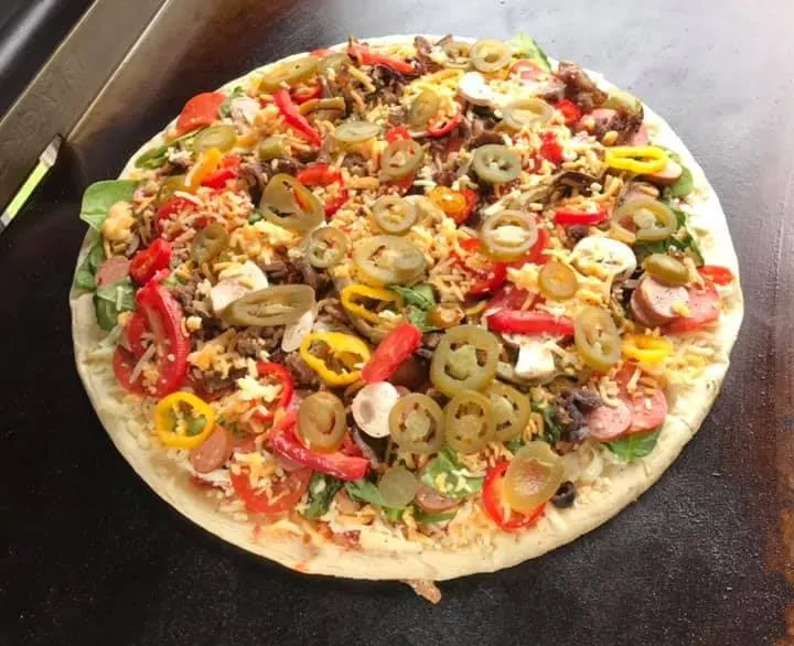 Pizza with toppings on a Blackstone griddle