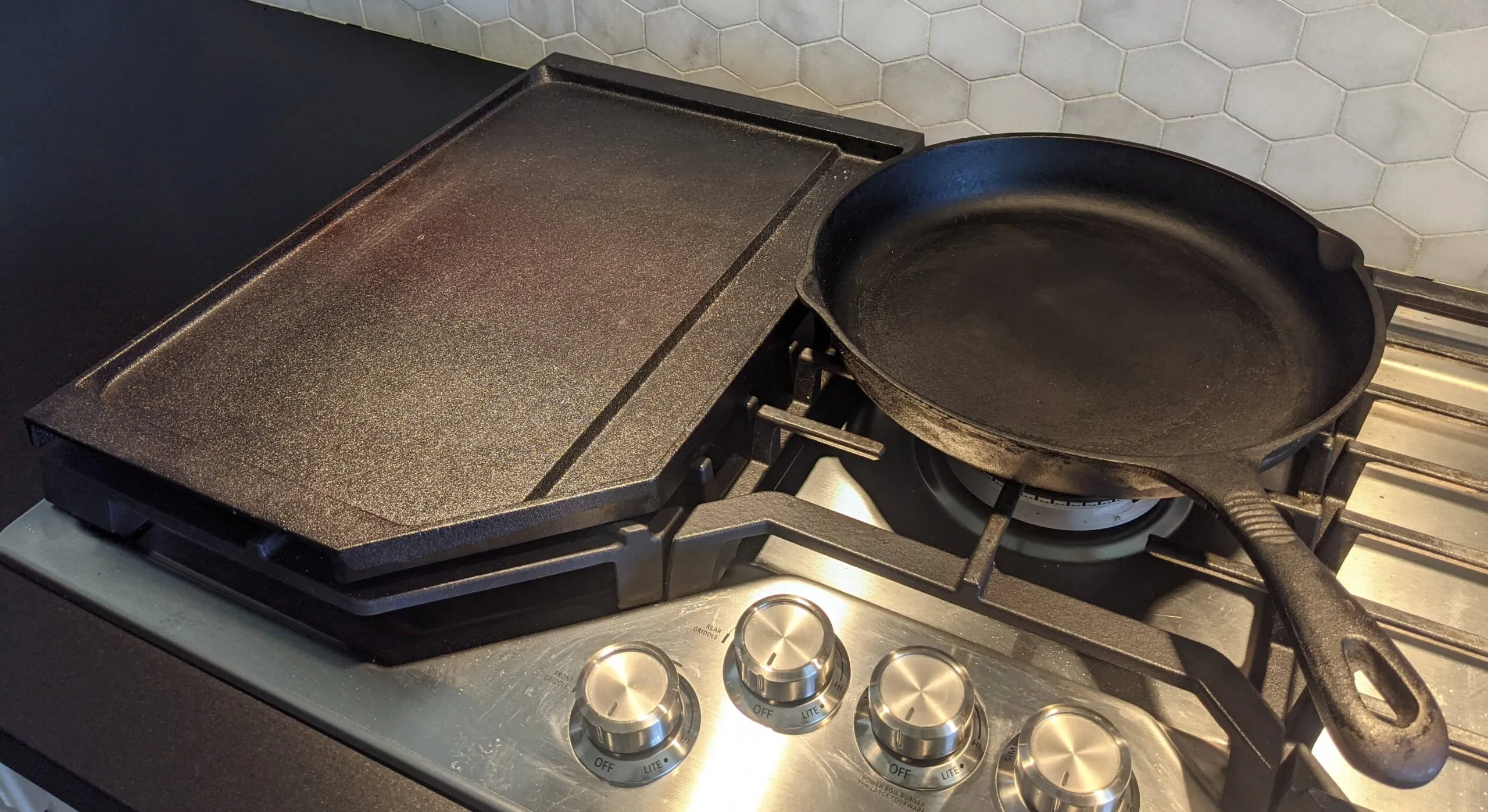 Flat griddle pan and cast iron skillet on a stovetop