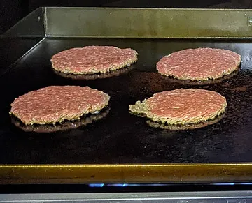 Smash burger patties just after pressing, crust forming