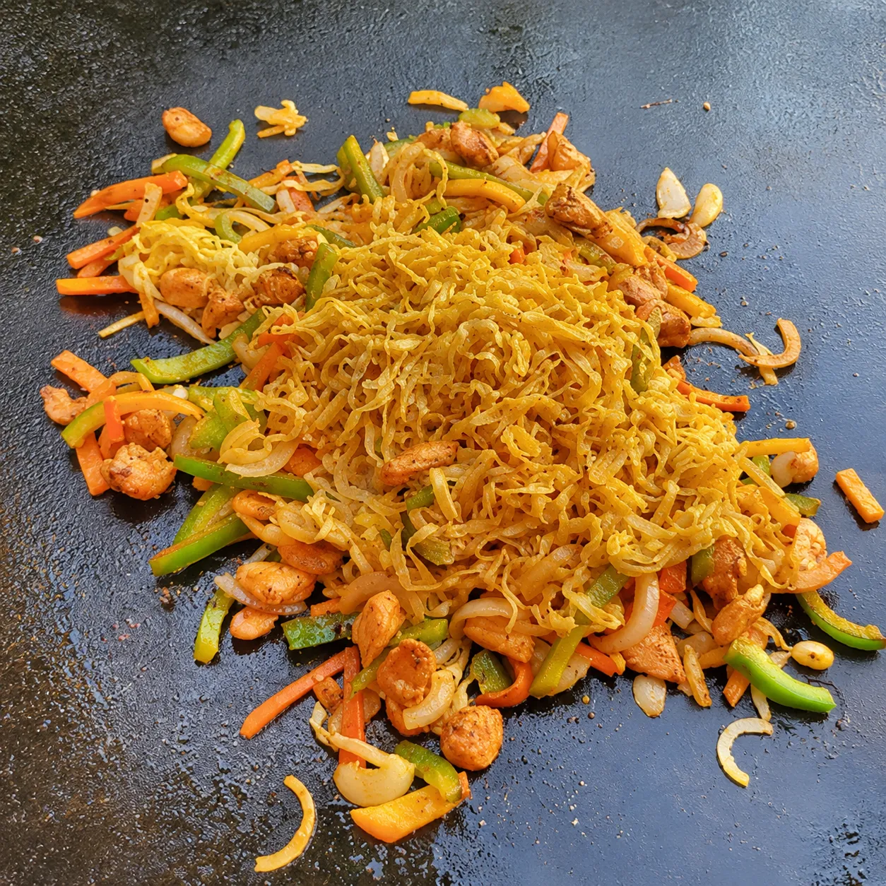 Blackstone chicken stir fry with noodles and vegetables on the flat-top griddle