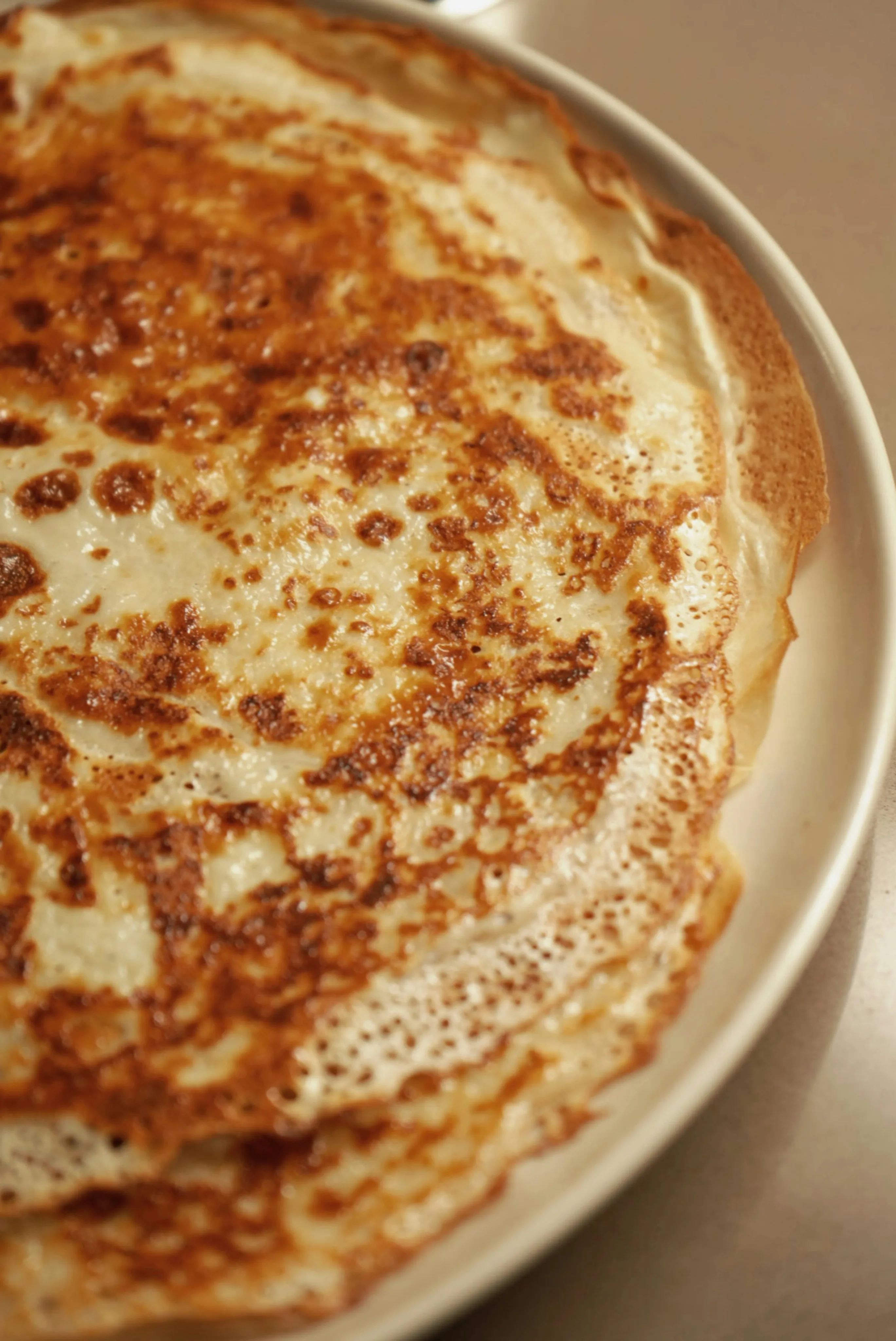 Thin golden crepe cooking on a Blackstone griddle flat top