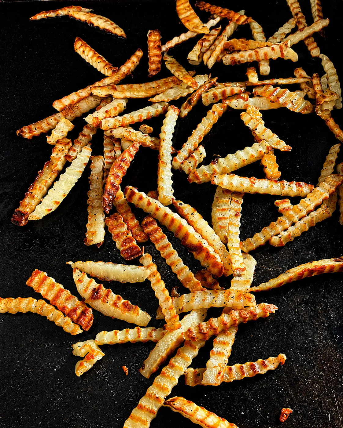 Crispy golden french fries cooking on a Blackstone flat-top griddle