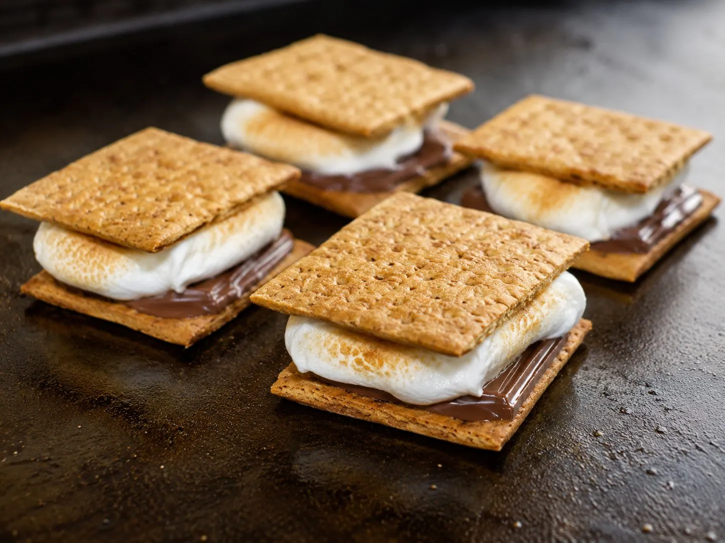 Assembled s'mores with toasted marshmallows and melted chocolate on a Blackstone griddle