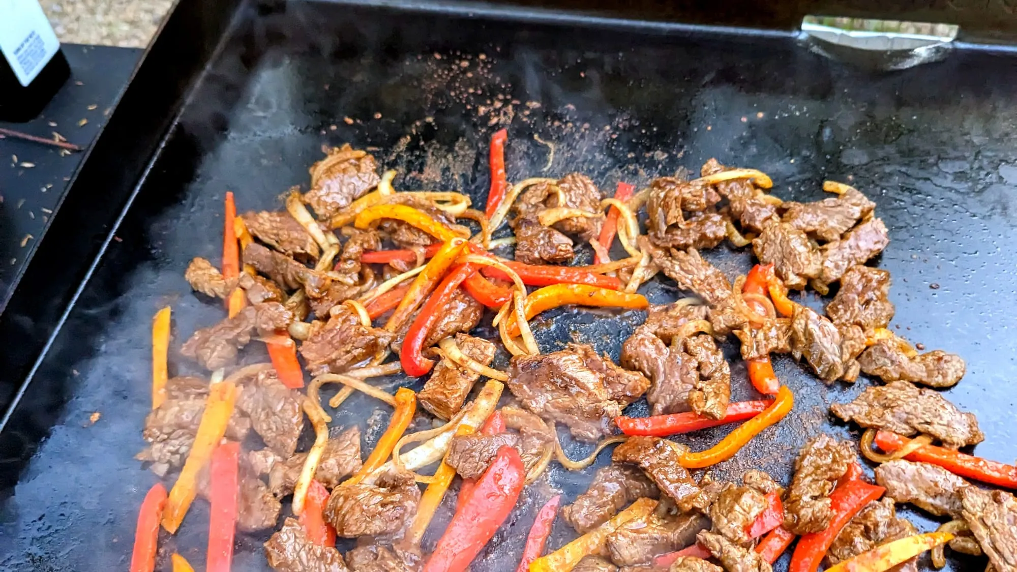Blackstone steak fajitas with skirt steak, caramelized peppers and onions on a flat-top griddle